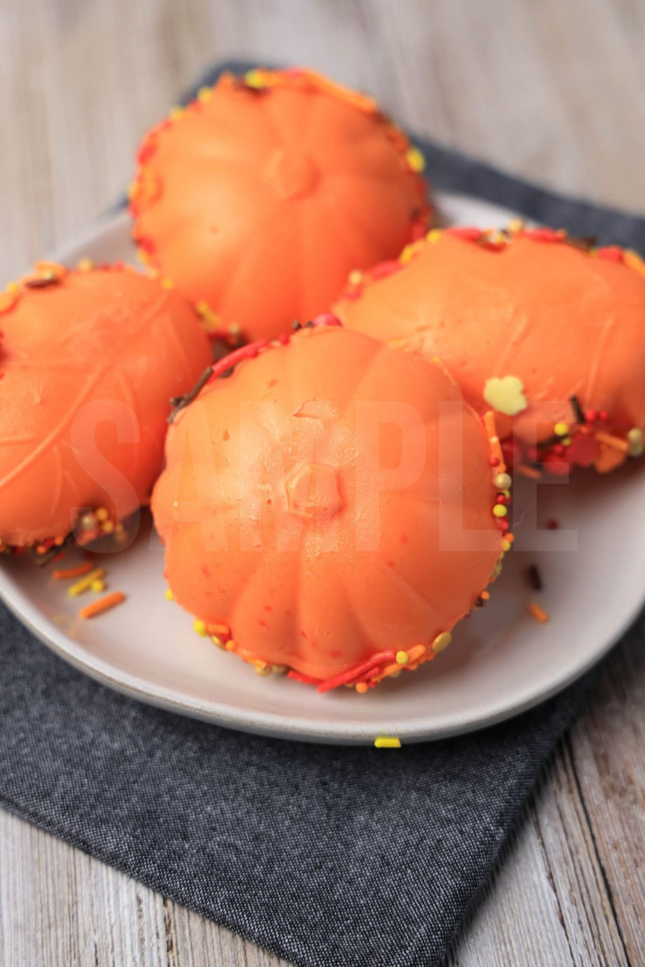 The Fall Pumpkin Spiced Chocolate Bomb comes on white plate with a denim napkin on a rustic wood backdrop.