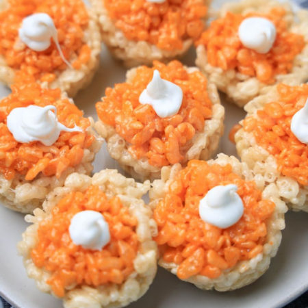 The Pumpkin Pie Rice Krispies Treats come on a white plate with a gray striped napkin on a marble backdrop.