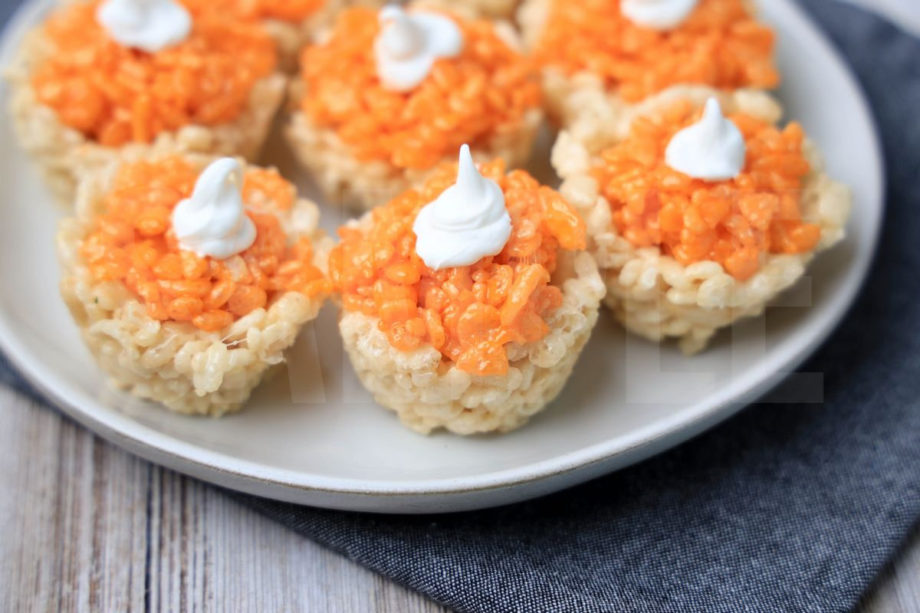 The Pumpkin Pie Rice Krispies Treats come on a white plate with a denim napkin on a rustic wood backdrop.