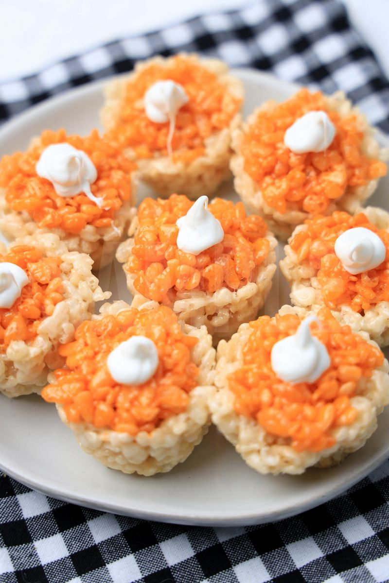 The Pumpkin Pie Rice Krispies Treats come on a white plate with a plaid napkin on a white wood backdrop.