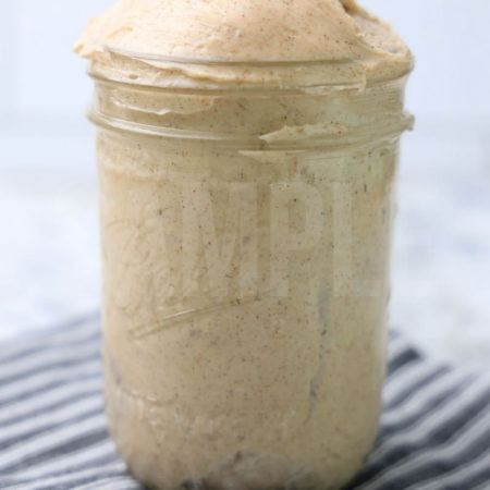The Copycat Texas Roadhouse Cinnamon Butter comes in a glass mason jar with a gray  striped napkin on a marble backdrop.