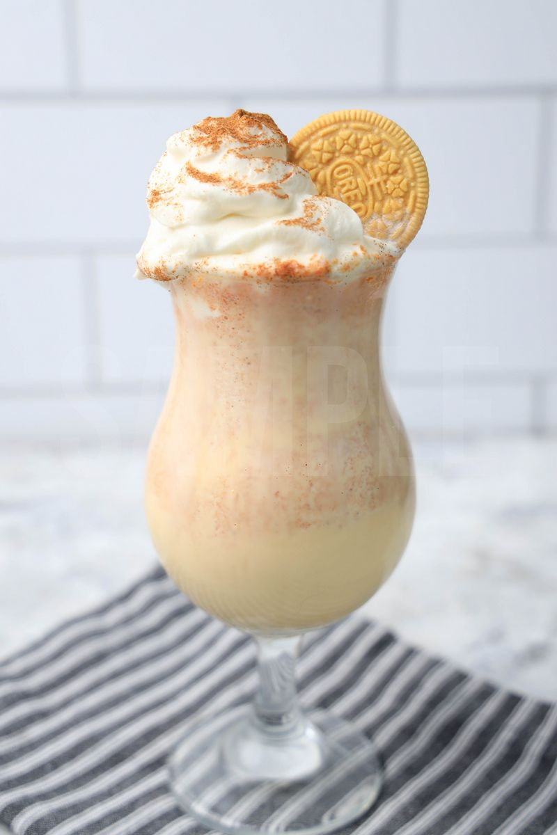 The Pumpkin Spiced Oreo Shake comes in a glass with a gray striped napkin on a marble backdrop.