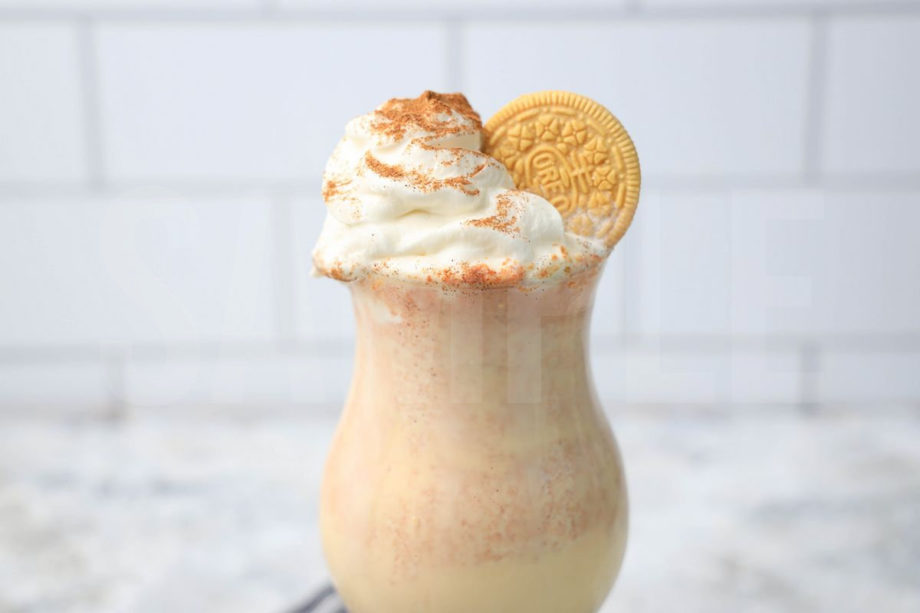 The Pumpkin Spiced Oreo Shake comes in a glass with a gray striped napkin on a marble backdrop.