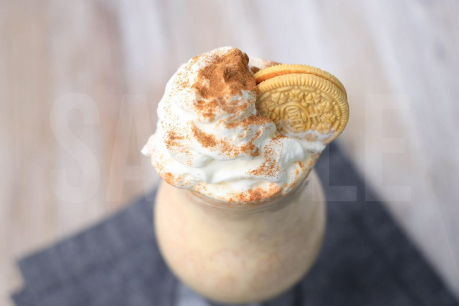 The Pumpkin Spiced Oreo Shake comes in a glass with a denim napkin on a rustic wood backdrop.