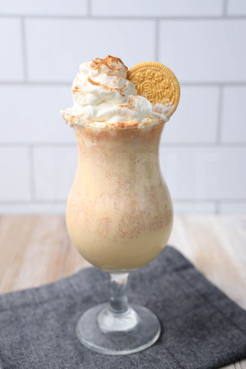 The Pumpkin Spiced Oreo Shake comes in a glass with a denim napkin on a rustic wood backdrop.