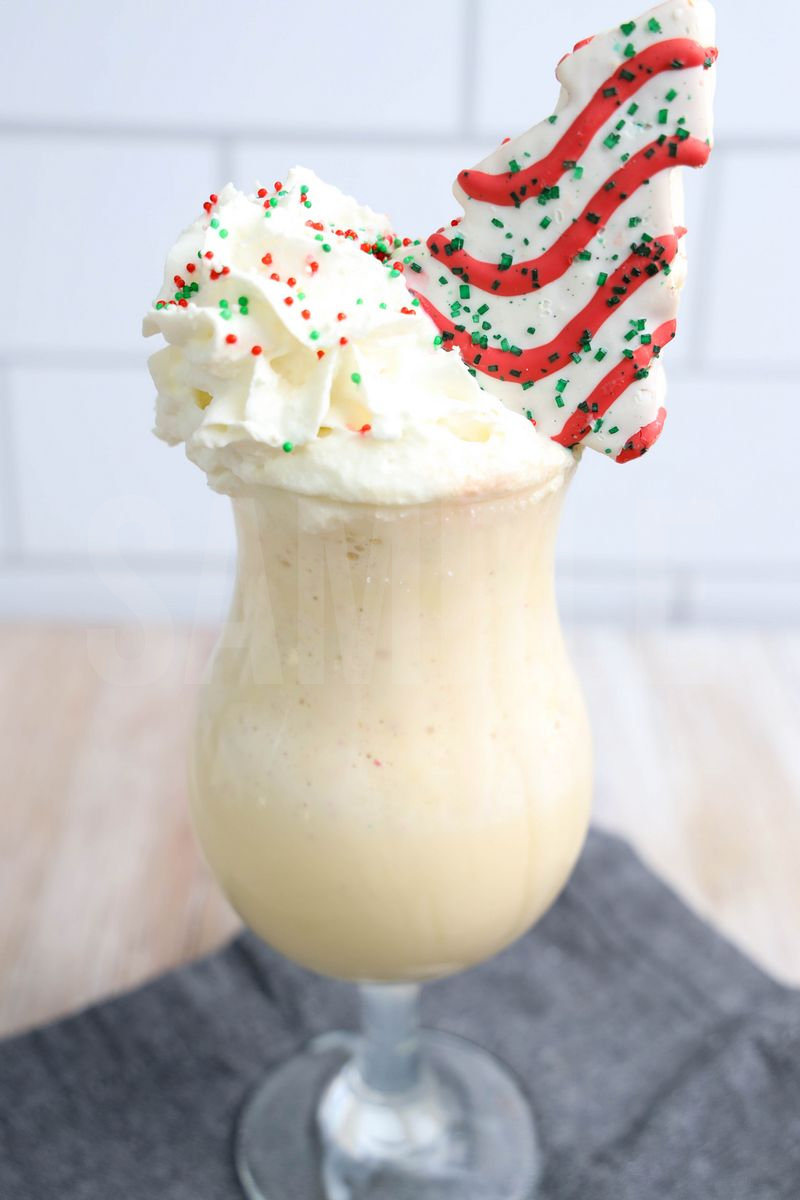 The Little Debbie's Christmas Tree Shake comes in a clear glass with a plaid napkin on a rustic wood backdrop.