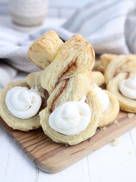 The Cinnamon Sugar Bunny Twists comes on a olive wood cutting board with gray and white cloth on white wood backdrop.