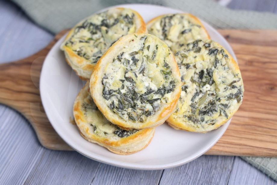 The Spinach Artichoke Easter Eggs comes on a white plate on a wood cutting board with a green cloth on a gray wood backdrop.