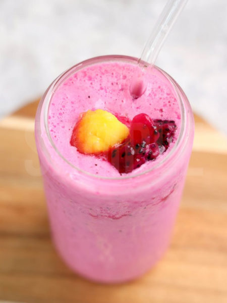 The dragonfruit smoothie comes in a glass can glass with marble wood backdrop.