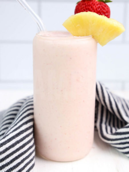 The tropical fruit smoothie comes in a glass can glass with white wood backdrop.